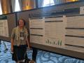 Alexis Boutin standing next to research poster at conference